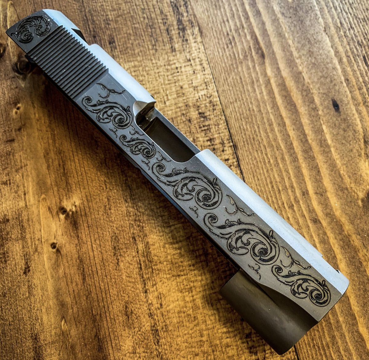 Pistol slide engraved with flowing scrollwork along its length