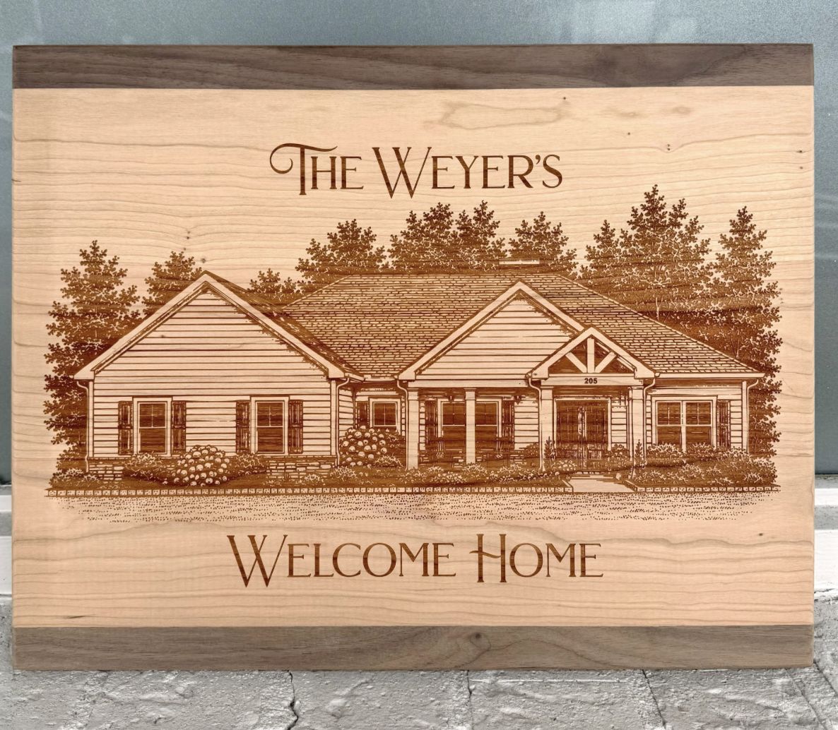 Wood sign engraved with a detailed drawing of a family's house